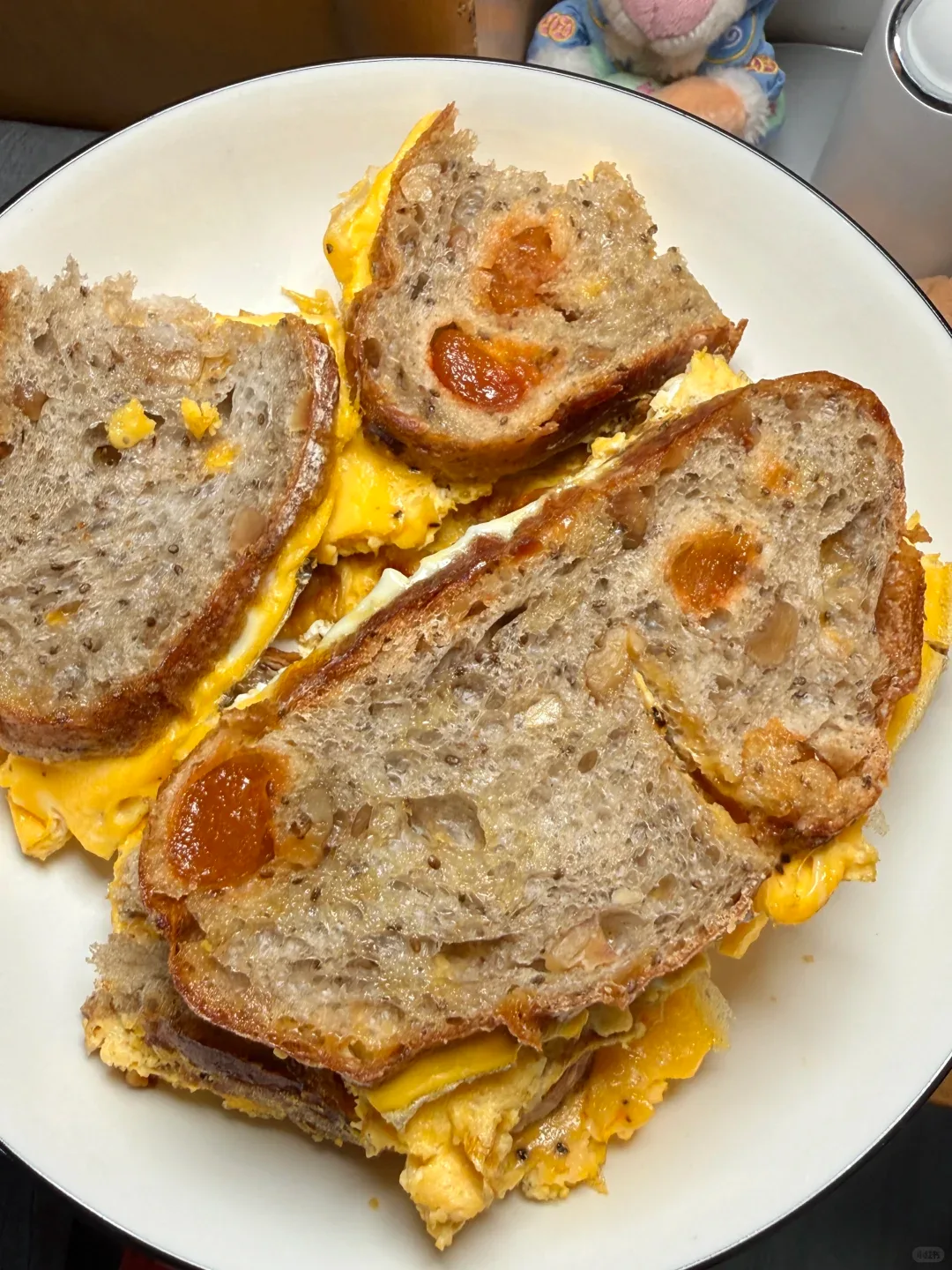 Bread sandwiches filled with folded egg, arranged on a cream plate.