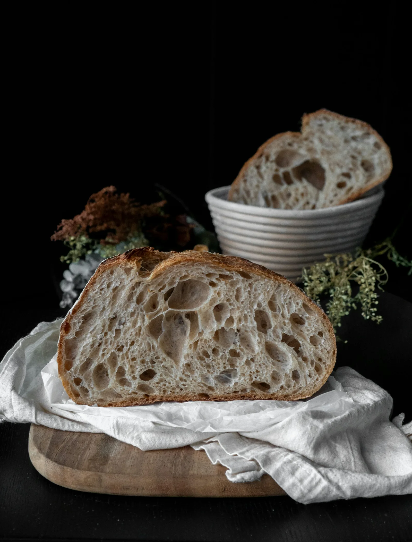 A crusty sourdough loaf opened to reveal a light crumb with large, irregular air pockets.
