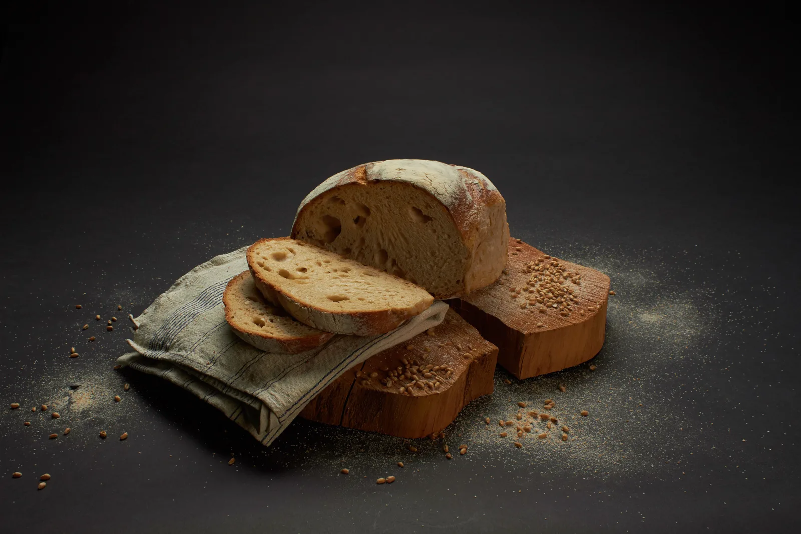A golden, flour-dusted rustic loaf with thick slices on a wooden board.